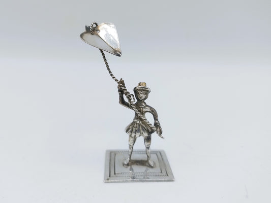 Zilveren miniatuurbeeldje, man met vlieger met lange ketting op sokkel