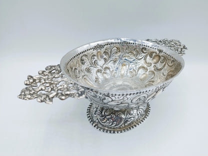 Zilveren brandewijnkom met rijk gegraveerde ornamenten en twee decoratieve handvatten