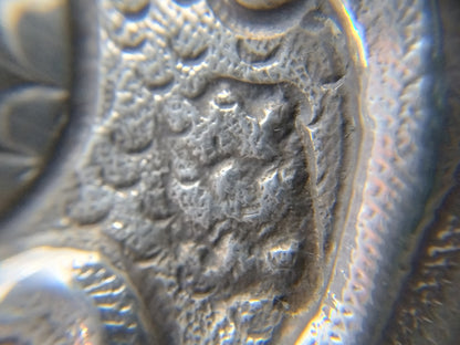 Close-up van reliëfgravure op zilveren brandewijnkom, met decoratief patroon
