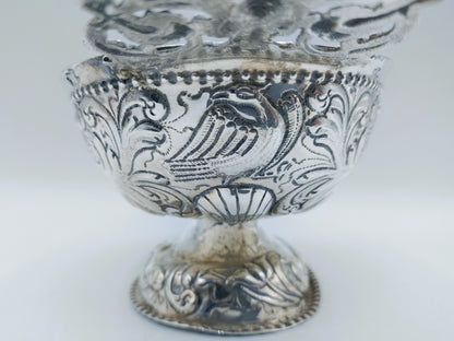Zilveren brandewijnkom met gegraveerd bloemen- en figuurmotief op de voet
