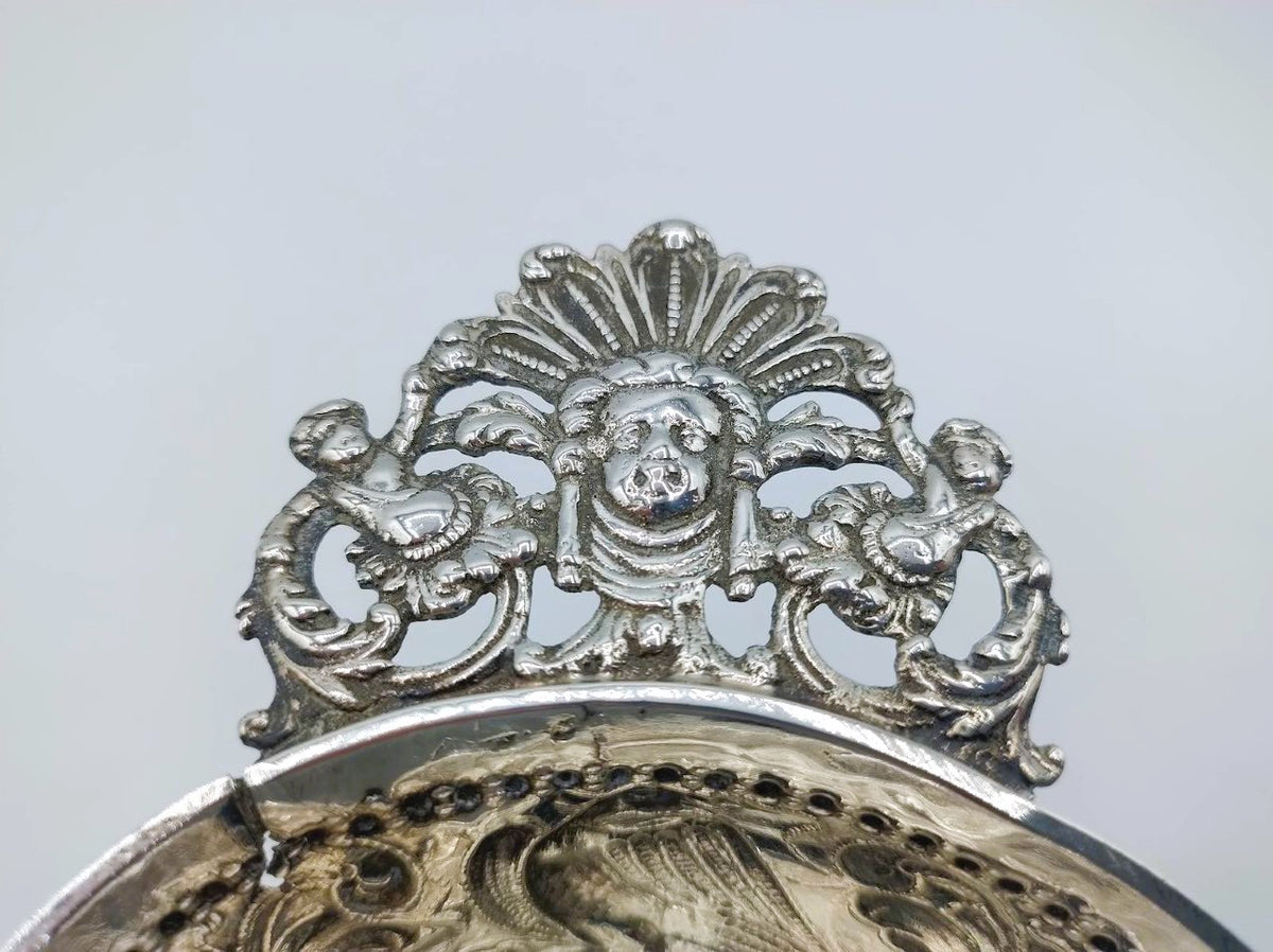 Zilveren brandewijnkom: close-up van sierrand met cartouche en decoratieve figuren
