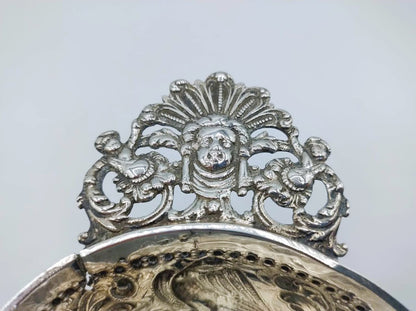 Zilveren brandewijnkom: close-up van sierrand met cartouche en decoratieve figuren