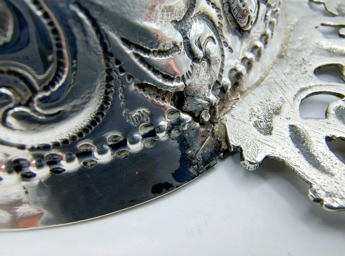 Zilveren brandewijnkom: detail van gravure met parelrand en bloemenornament