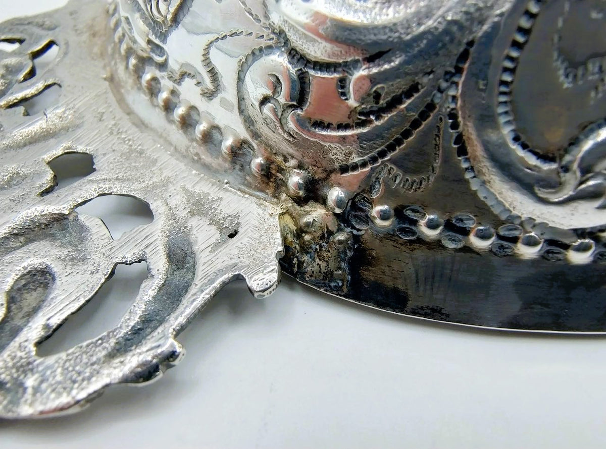 Zilveren brandewijnkom: detail van gegraveerde rand met parelwerk en ornament