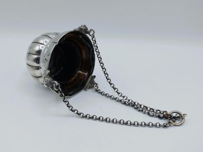 Zilveren altaarlamp met ketting en donker glas in metalen houder.