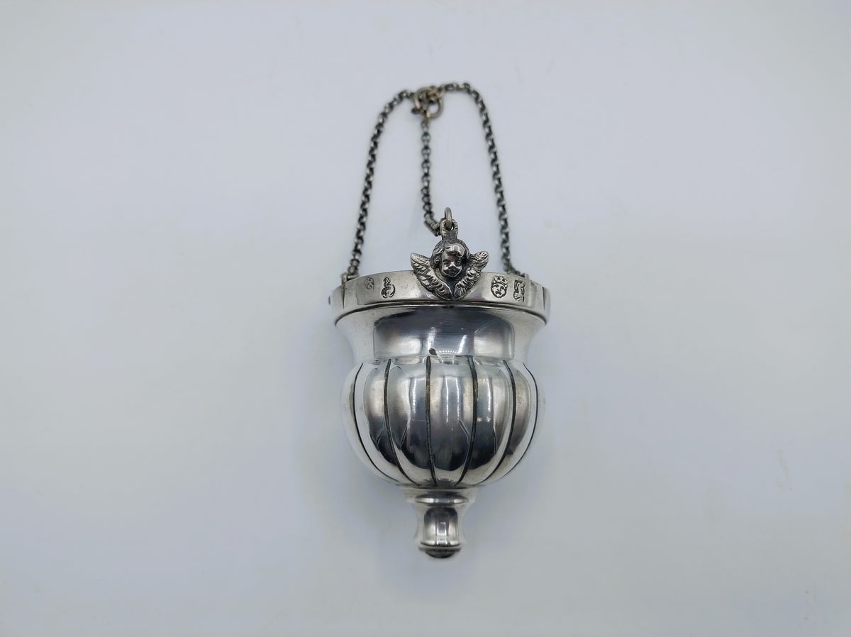 Zilveren altaarlamp met opgehangen kettingen en ronde glazen bak.