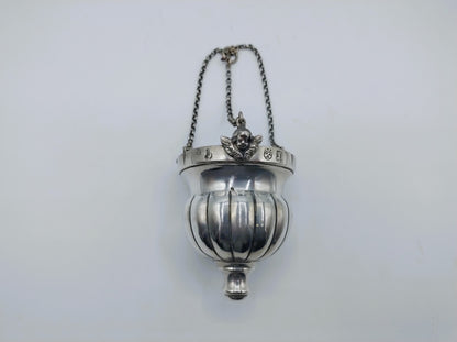 Zilveren altaarlamp met opgehangen kettingen en ronde glazen bak.