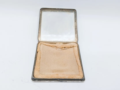 Open zilveren poederdoos met beige poederkussen in opbergvak