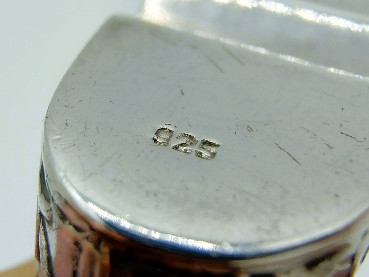 Close-up van zilveren onderkant met 925 keurmerk op speldenkussen