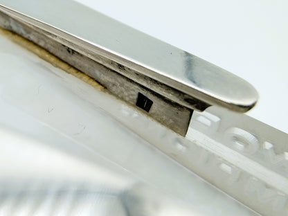 Close-up van metalen blade en ingesneden witte basis met zwarte rechthoekige inzet.