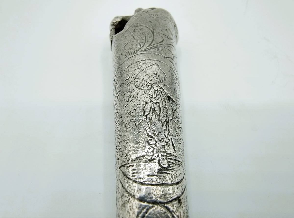 Close-up van zilveren heft met reliëfgravure van een figuur en bloemenmotief.