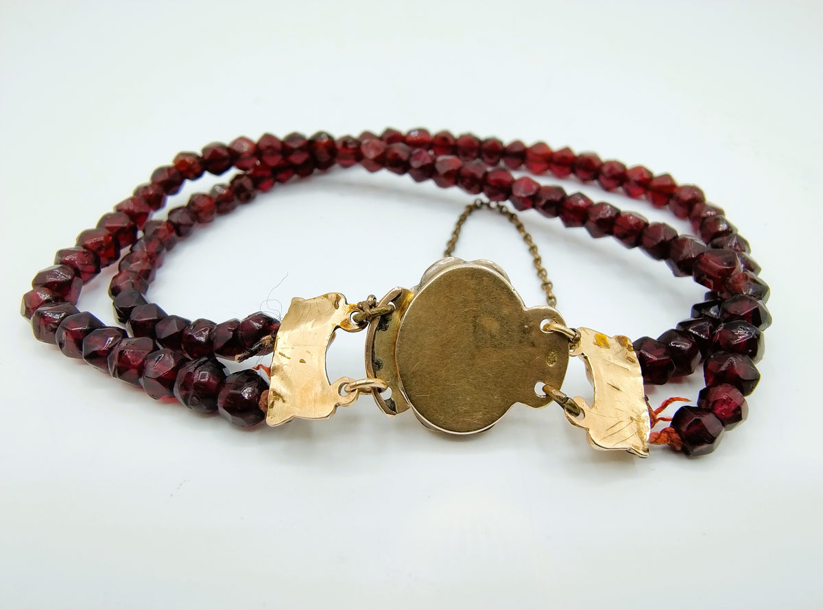 Glasgranaten armband met rode kralen en goudkleurige ronde sluitplaat met ketting
