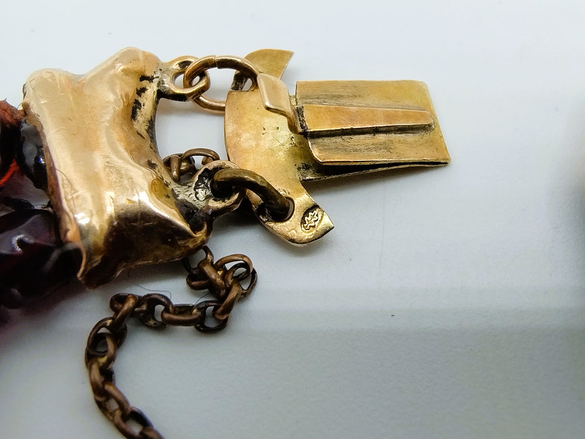 Close-up van gouden slot met ring en ketting aan rode glasgranaten armband