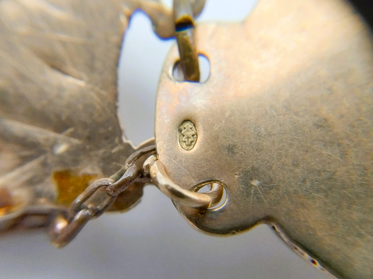 Close-up van gouden sluiting met gegraveerd merkteken en kettingschakels