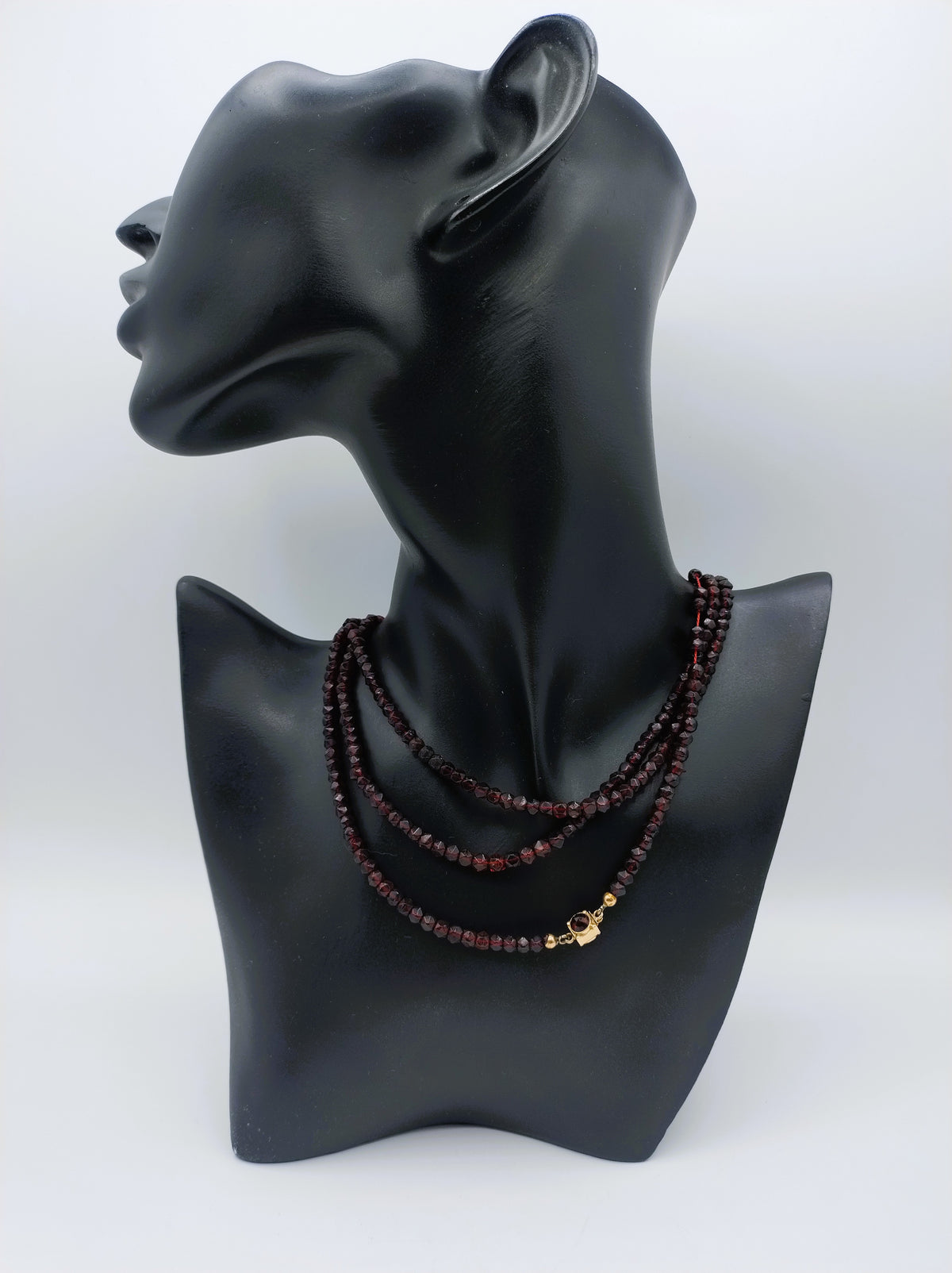 Kralenketting met bordeauxrode glasparels en gouden slotje, gedragen op paspop.