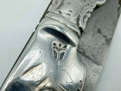 Close-up van zilveren zakmes met reliëfdecor op het heft en rand van lemmet