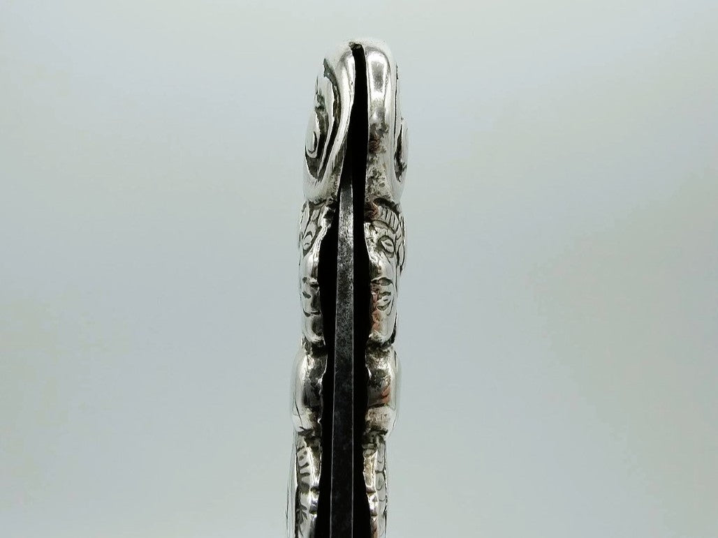 Zilveren zakmes zijaanzicht met gegraveerde zijkanten en smalle opening