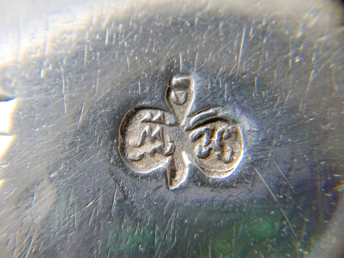 Zilveren stempel met ruit- en bloemmotief op het oppervlak