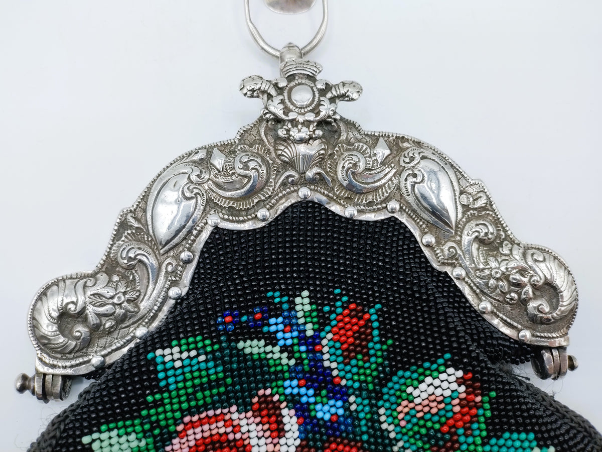 Close-up zilveren rokhaak met zwart borduurwerk en kleurrijk patroon