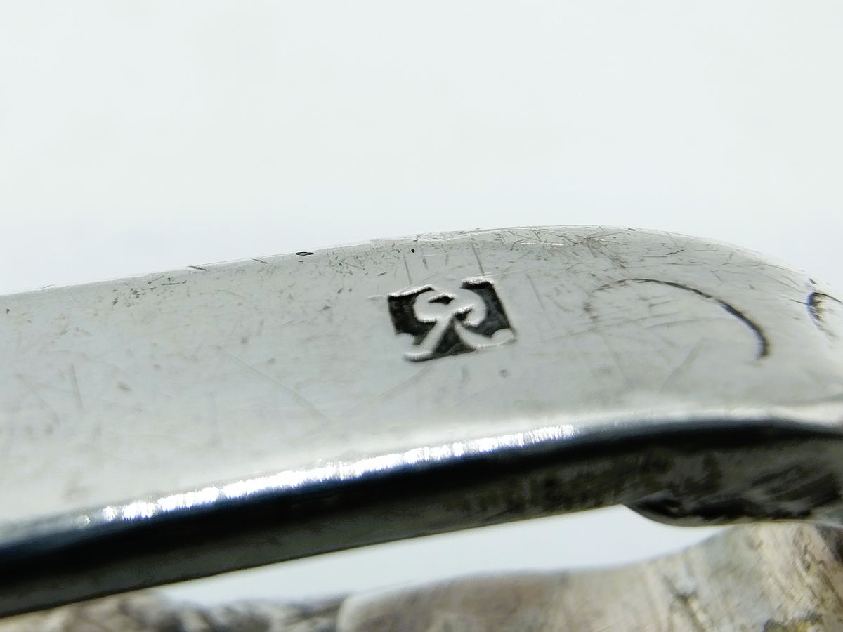 Zilveren tasbeugel, close-up van gegraveerd merkteken op de beugel
