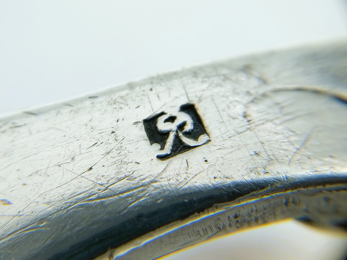 Zilveren tasbeugel, close-up merkteken en zilveren rand