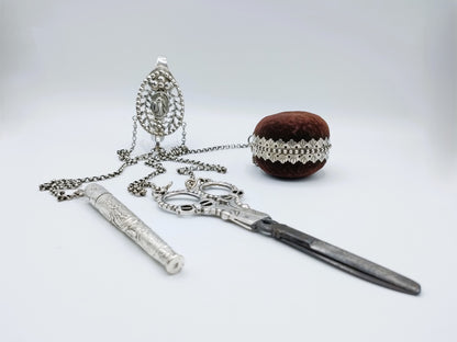 Zilveren chatelaine met ketting, twee hangers, zakmes, schaar en fluwelen prop