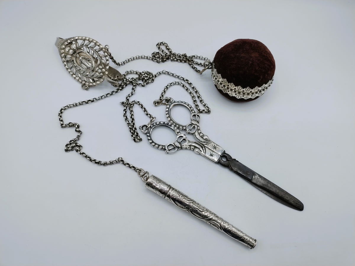 Zilveren chatelaine met ketting, schaar, zakmes en fluwelen prop in het midden