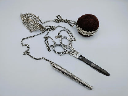 Zilveren chatelaine met ketting, schaar, zakmes en fluwelen prop in het midden