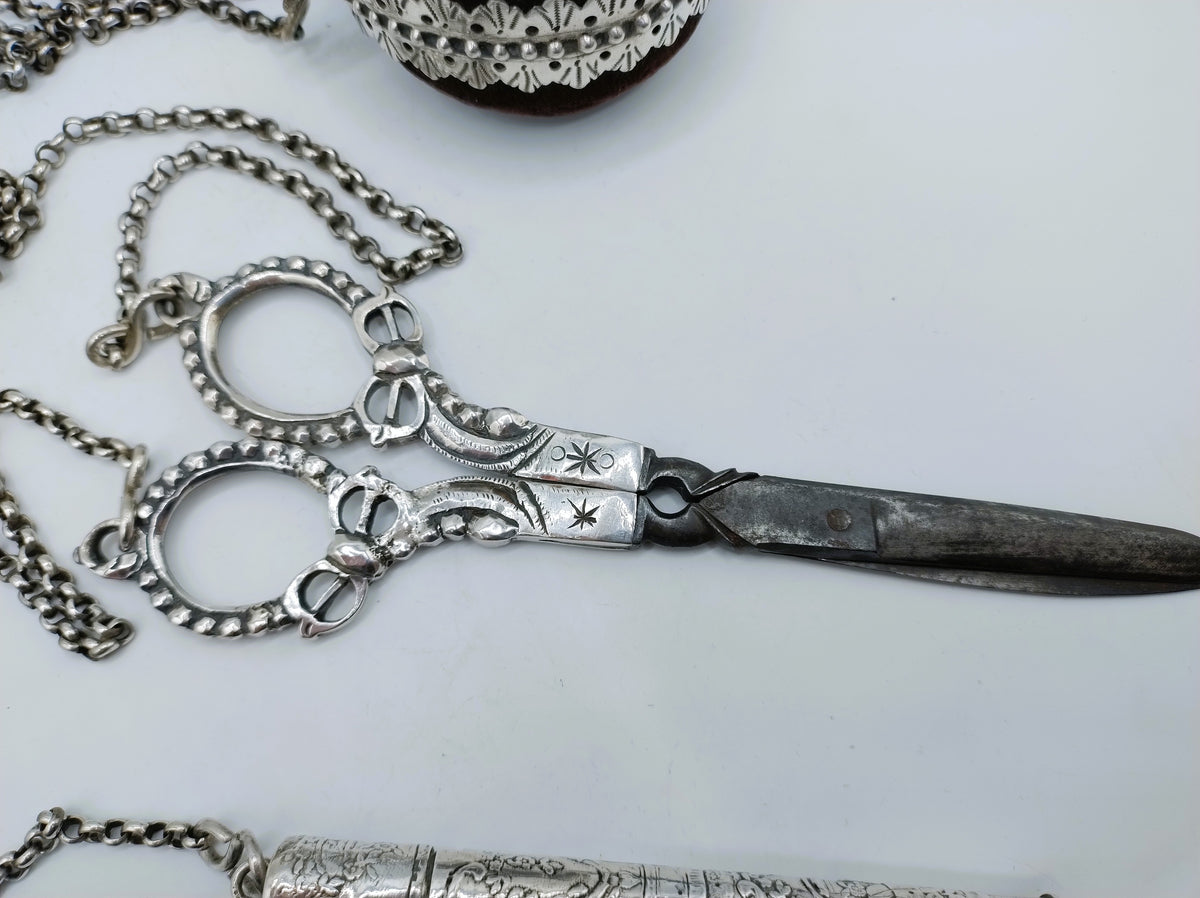 Zilveren chatelaine met ketting en scharnierende schaar; ringvormige sluiting zichtbaar