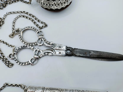 Zilveren chatelaine met ketting en scharnierende schaar; ringvormige sluiting zichtbaar