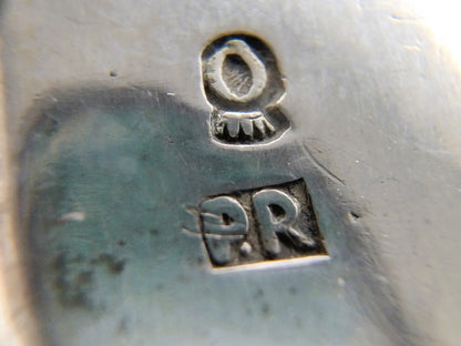 Zilveren keurmerkstempel met 'PR' en oogvormig symbool op chatelaine-onderdeel