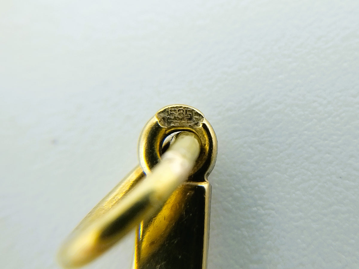 Detail van het ophangoog met keurmerk op de gouden kruishanger