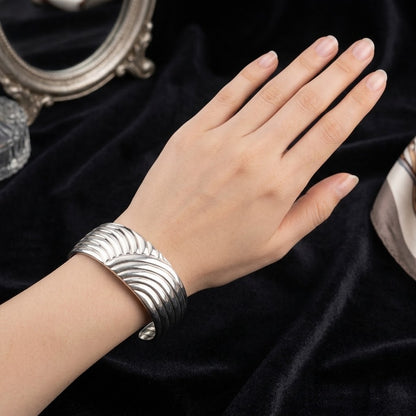 Zilveren cuff armband met golfmotief en geribbelde randen, brede sluiting.