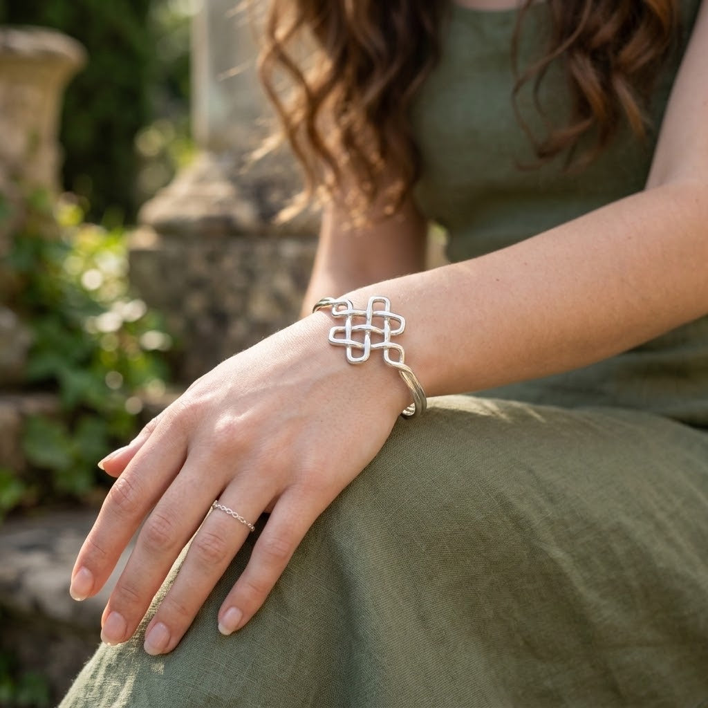 Zilveren armband met keltische knoop op pols, open manche met gevlochten schakels