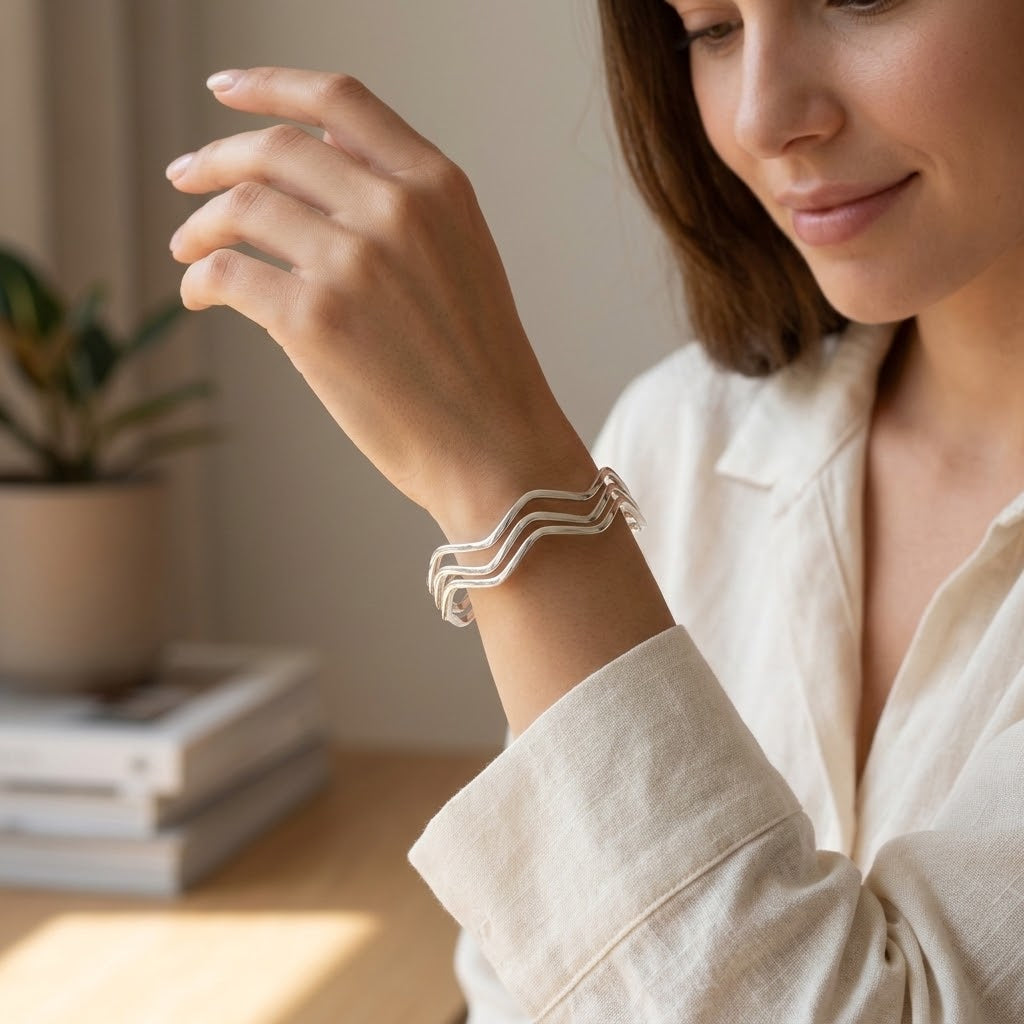 Set van drie zilveren bangle-armbanden (925), gestapeld op pols.